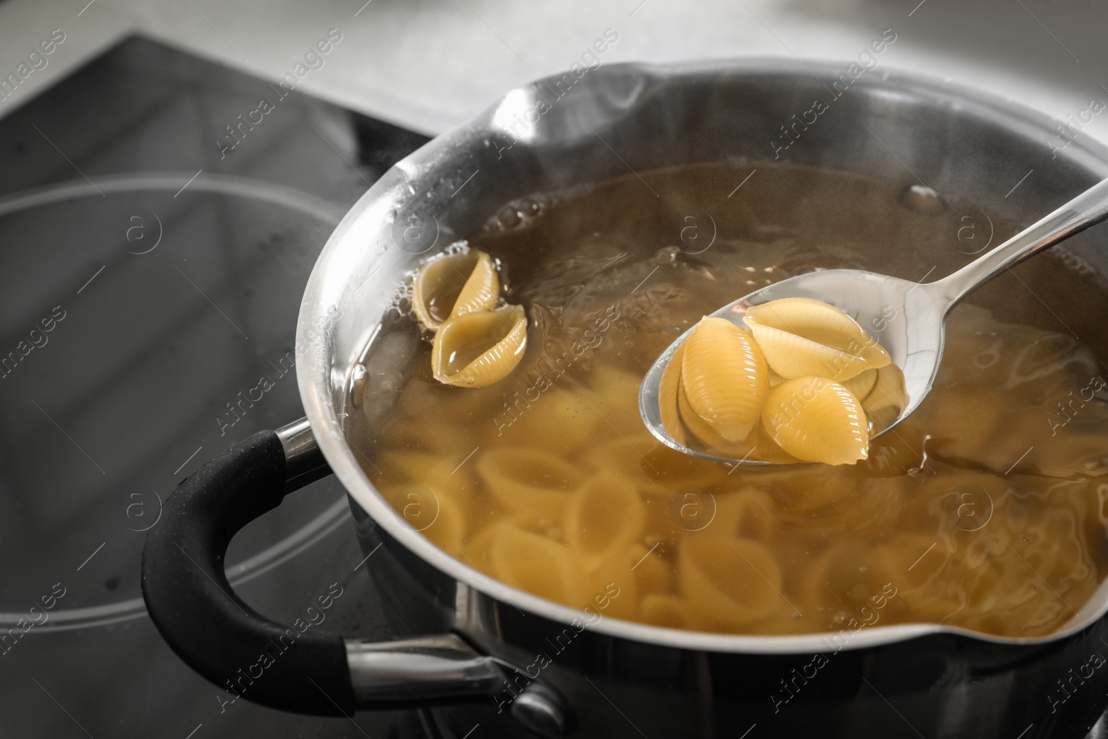 Photo of Cooking pasta in pot on electric stove, closeup view