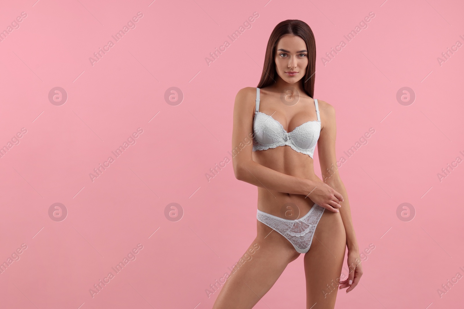 Photo of Young woman in elegant white underwear on pink background. Space for text