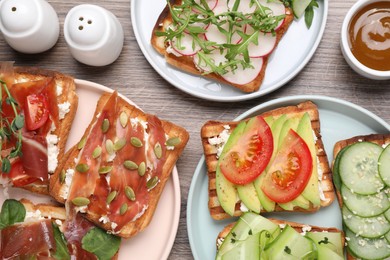 Photo of Different tasty sandwiches served on wooden table, flat lay