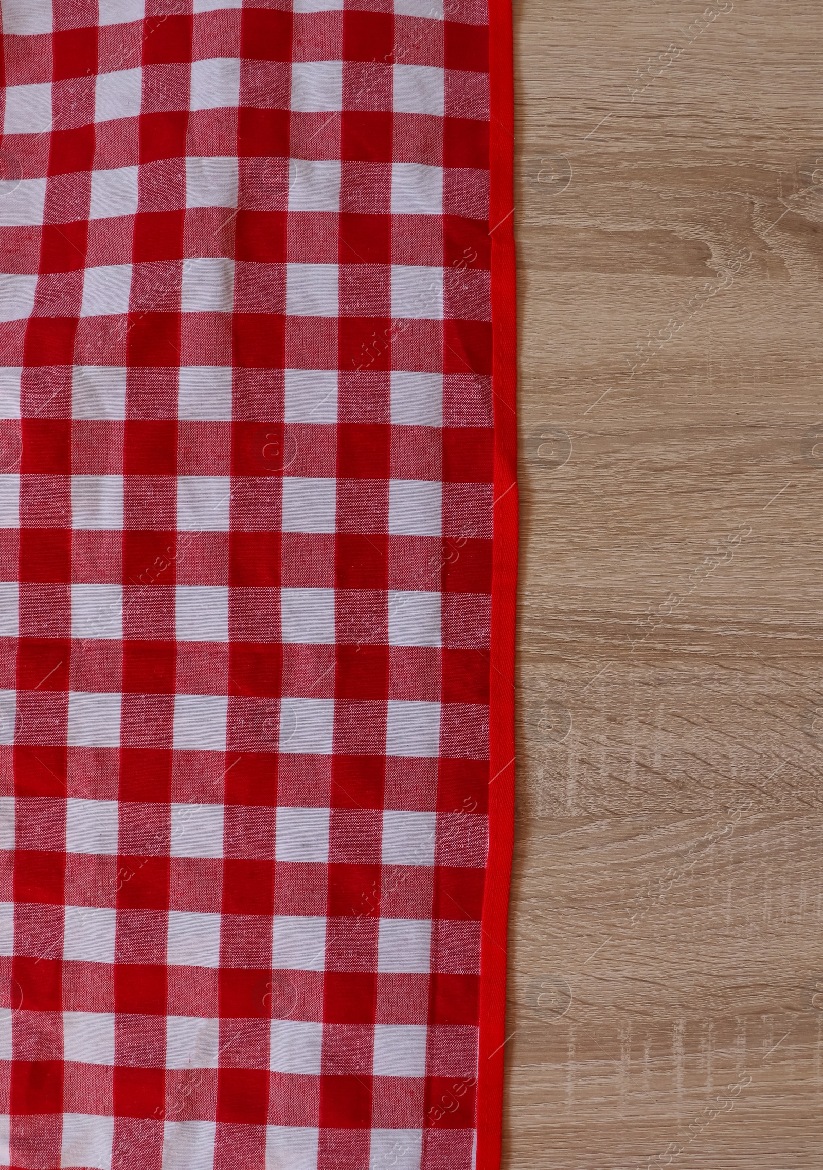 Photo of Checkered picnic cloth on wooden table, top view. Space for text