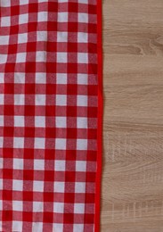 Checkered picnic cloth on wooden table, top view. Space for text