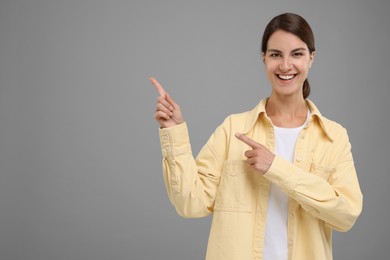 Photo of Special promotion. Happy woman pointing at something on grey background, space for text