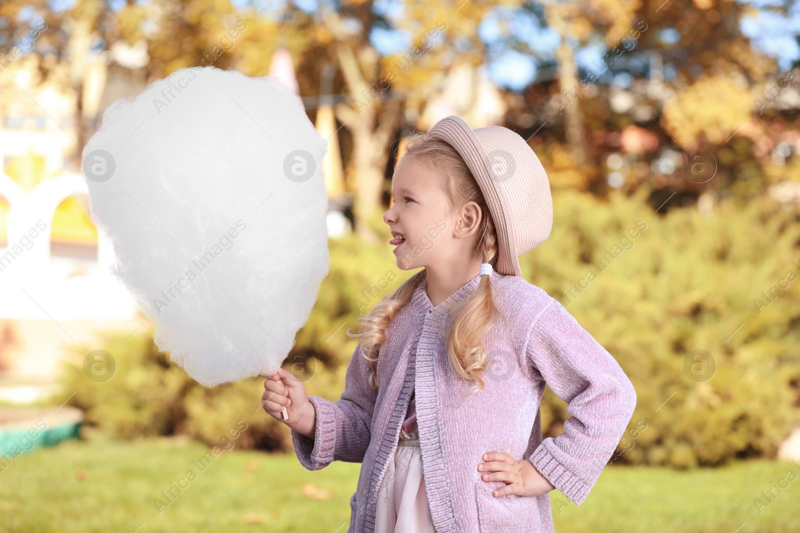 Photo of Cute little girl with cotton candy outdoors