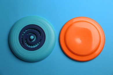 Plastic frisbee disks on light blue background, flat lay