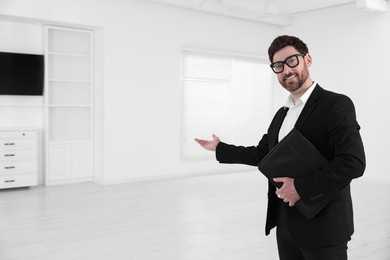 Happy real estate agent with leather portfolio showing new apartment. Space for text