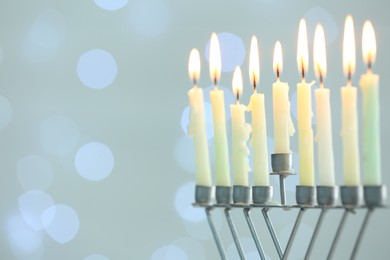 Hanukkah celebration. Menorah with burning candles against blurred lights, space for text