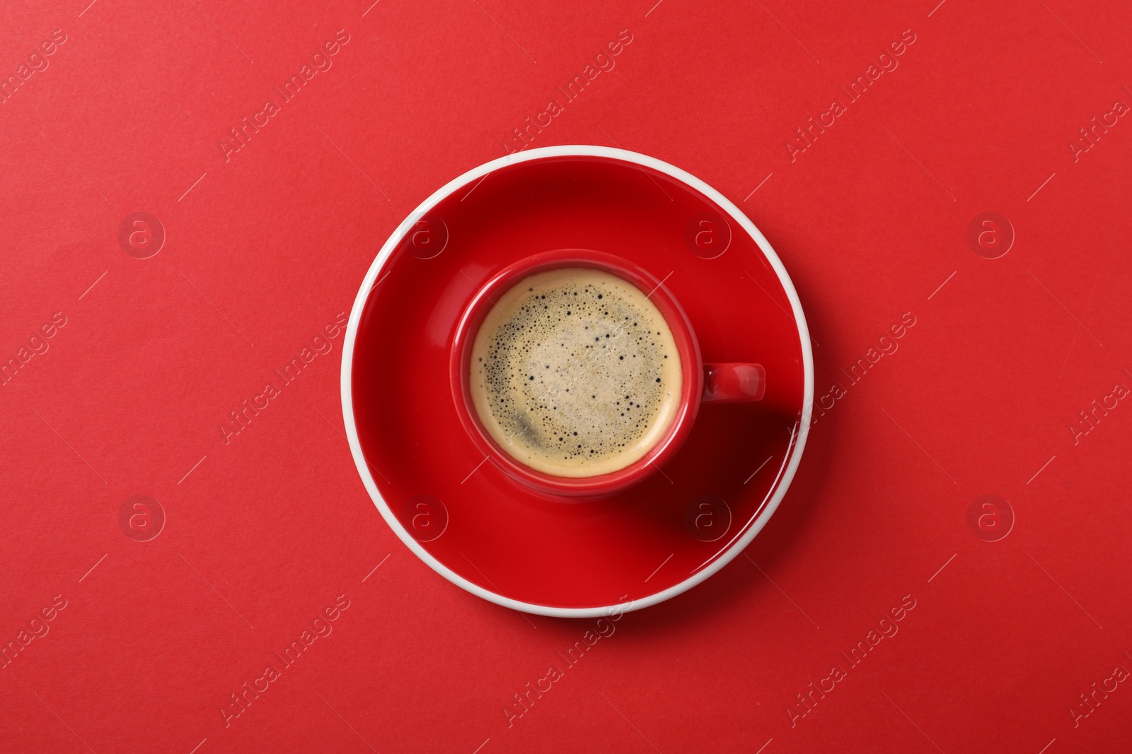 Photo of Tasty coffee in cup on red background, top view