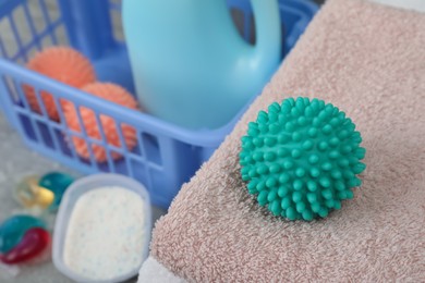 Turquoise dryer ball and clean towels on table, closeup