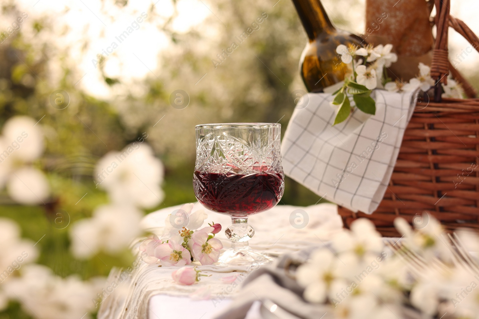 Photo of Stylish table setting with beautiful spring flowers and wine in garden