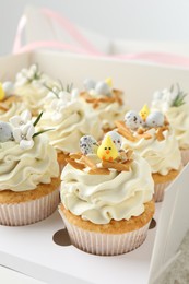 Photo of Tasty Easter cupcakes with vanilla cream in box, closeup