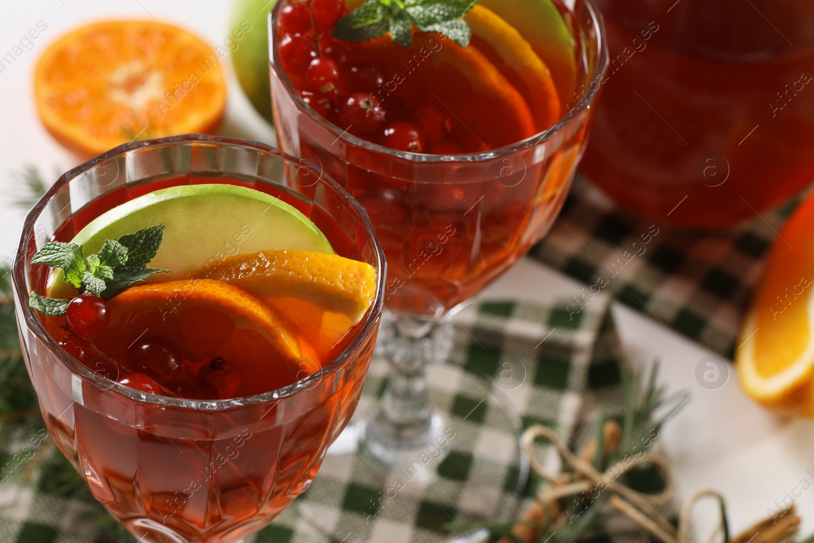 Photo of Christmas Sangria cocktail in glasses and ingredients on white table, closeup. Space for text