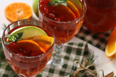 Photo of Christmas Sangria cocktail in glasses and ingredients on white table, closeup. Space for text