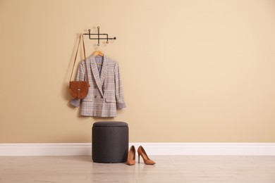 Stylish comfortable pouf near beige wall in hallway, space for text