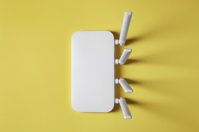 Photo of New white Wi-Fi router on yellow background, top view