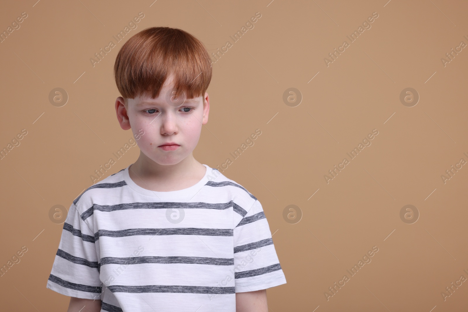 Photo of Portrait of sad little boy on beige background, space for text