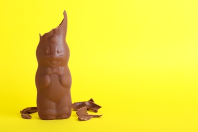 Photo of Broken chocolate Easter bunny on yellow background. Space for text