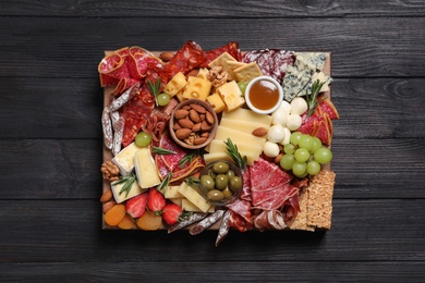 Photo of Assorted appetizers served on black wooden table, top view