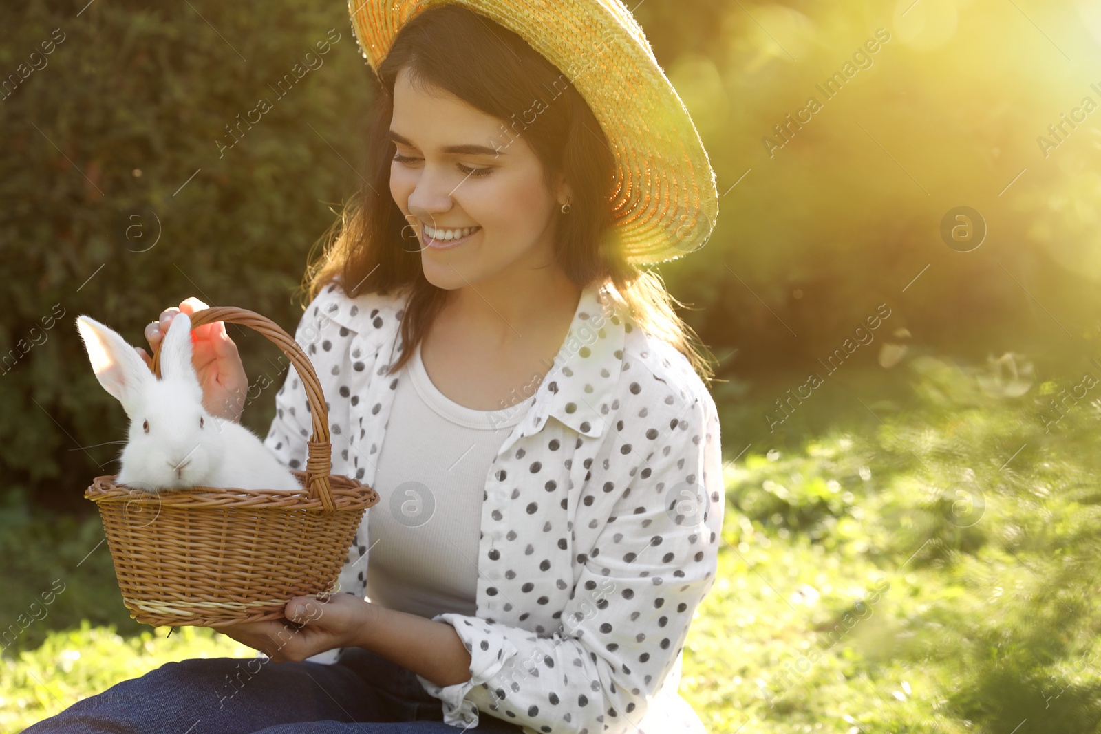 Photo of Happy woman with cute rabbit on green grass outdoors