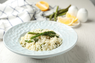 Photo of Delicious risotto with asparagus on white wooden table