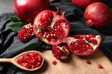 Photo of Ripe pomegranates and spoon with seeds on wooden board