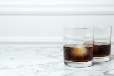 Photo of Cocktails with ice balls on white marble table, space for text