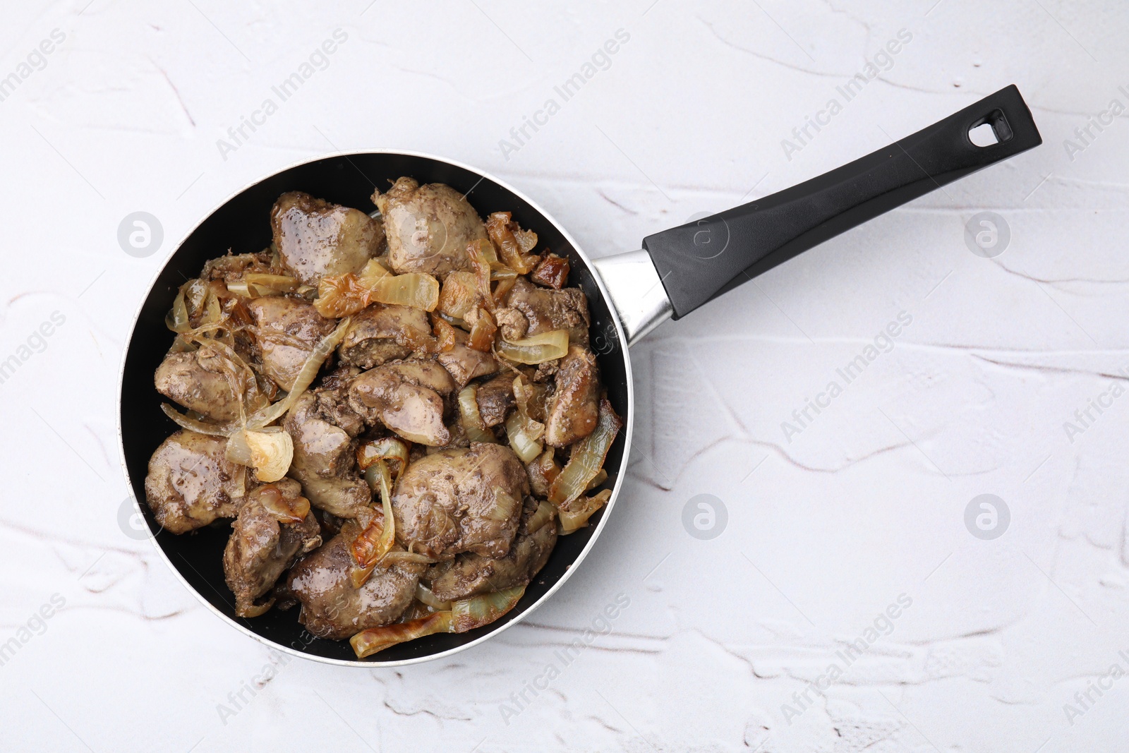 Photo of Pan with tasty fried chicken liver and onion on white textured table, top view