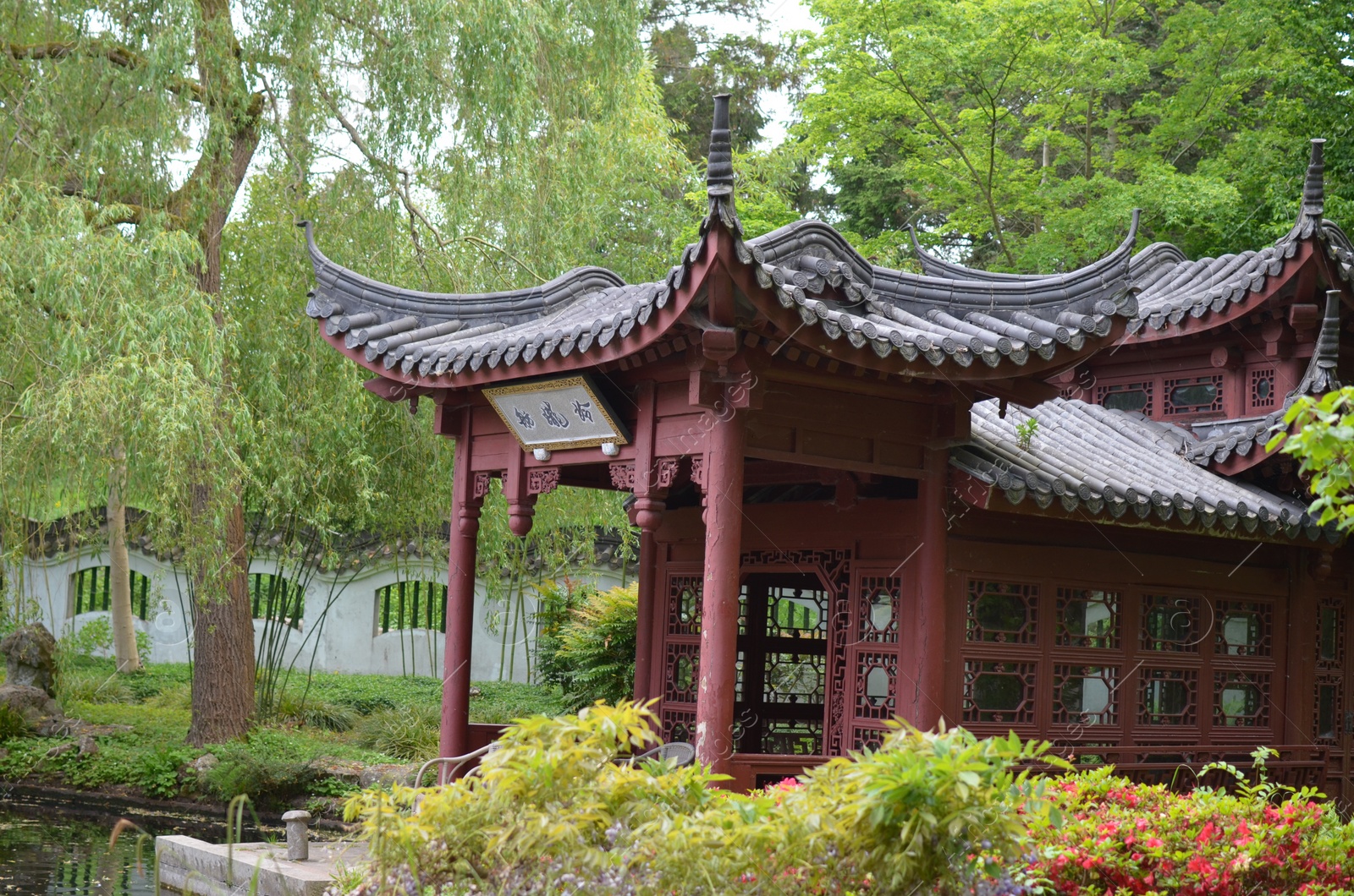 Photo of HAREN, NETHERLANDS - MAY 23, 2022: Beautiful view of oriental gazebo near pond in Chinese garden