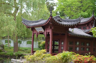 Photo of HAREN, NETHERLANDS - MAY 23, 2022: Beautiful view of oriental gazebo near pond in Chinese garden