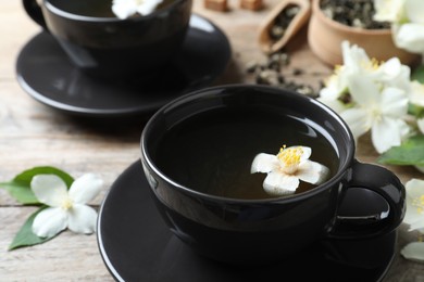 Cup of tea with fresh jasmine flower on table, closeup