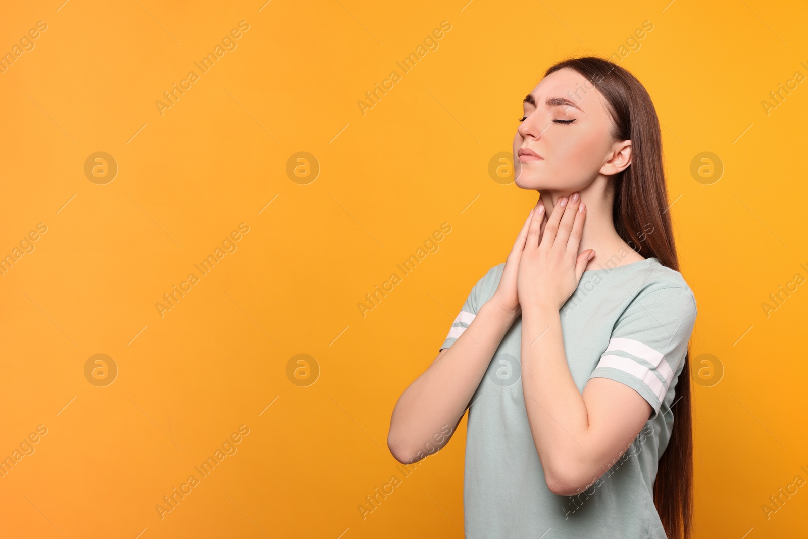 Photo of Young woman with sore throat on orange background. Space for text