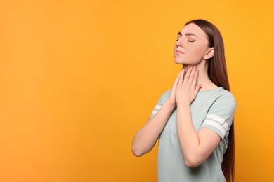 Photo of Young woman with sore throat on orange background. Space for text