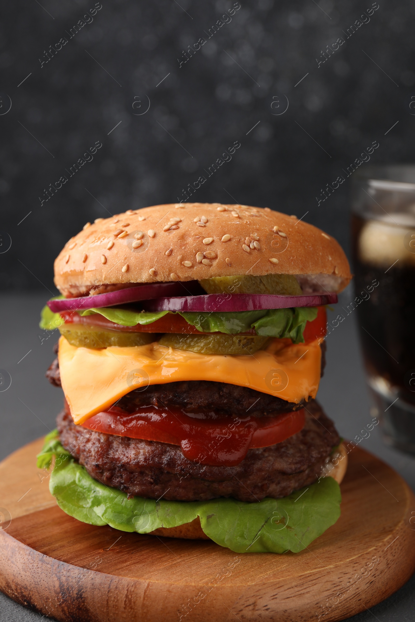 Photo of Tasty cheeseburger with patties and tomato on table, closeup