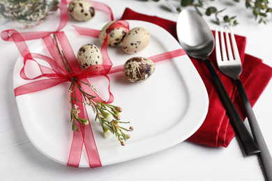Photo of Festive Easter table setting with ribbon, floral decor and quail eggs on white background