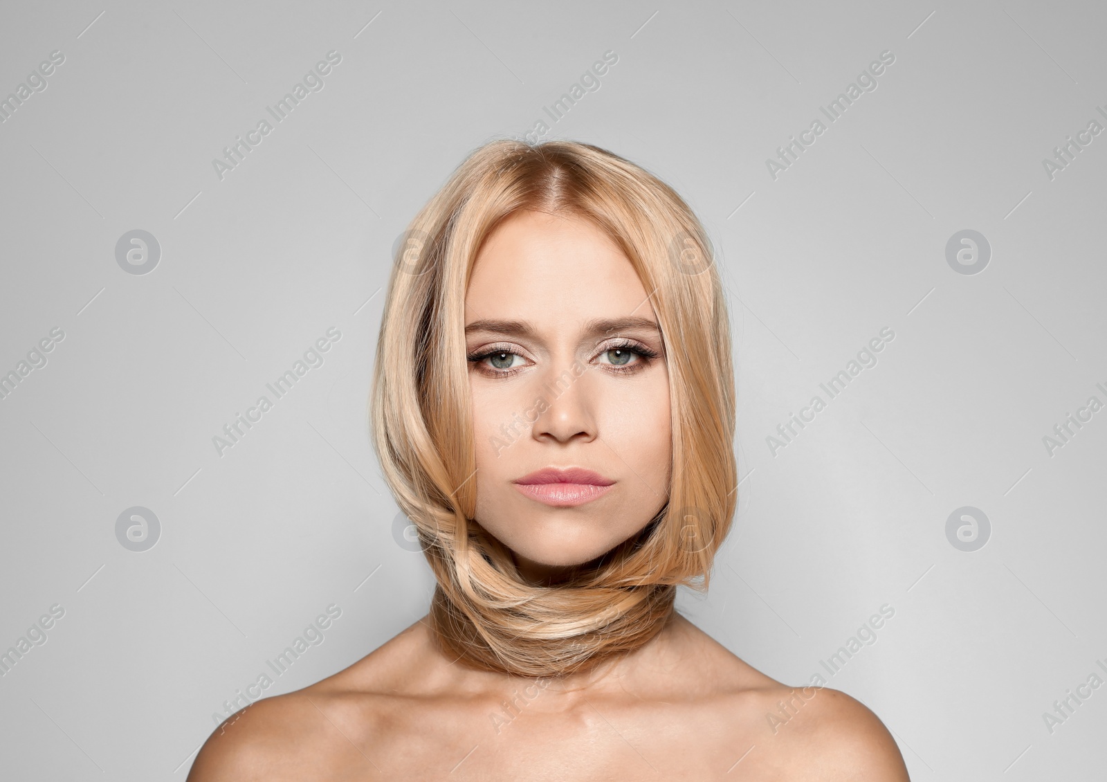 Photo of Beautiful woman with healthy long blonde hair on light background