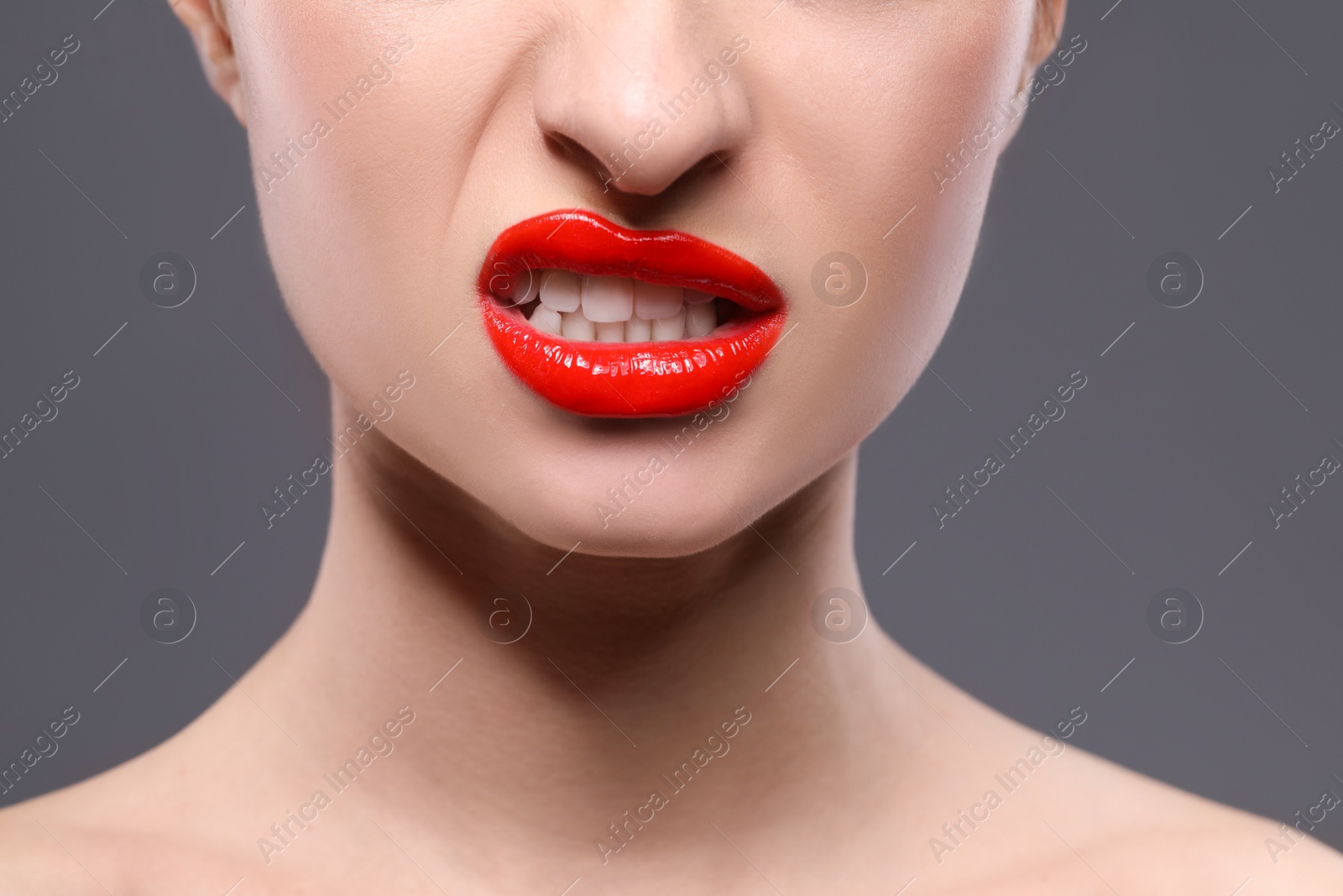 Photo of Young woman with beautiful red lips on grey background, closeup