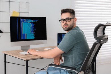 Photo of Happy young programmer working at desk in office