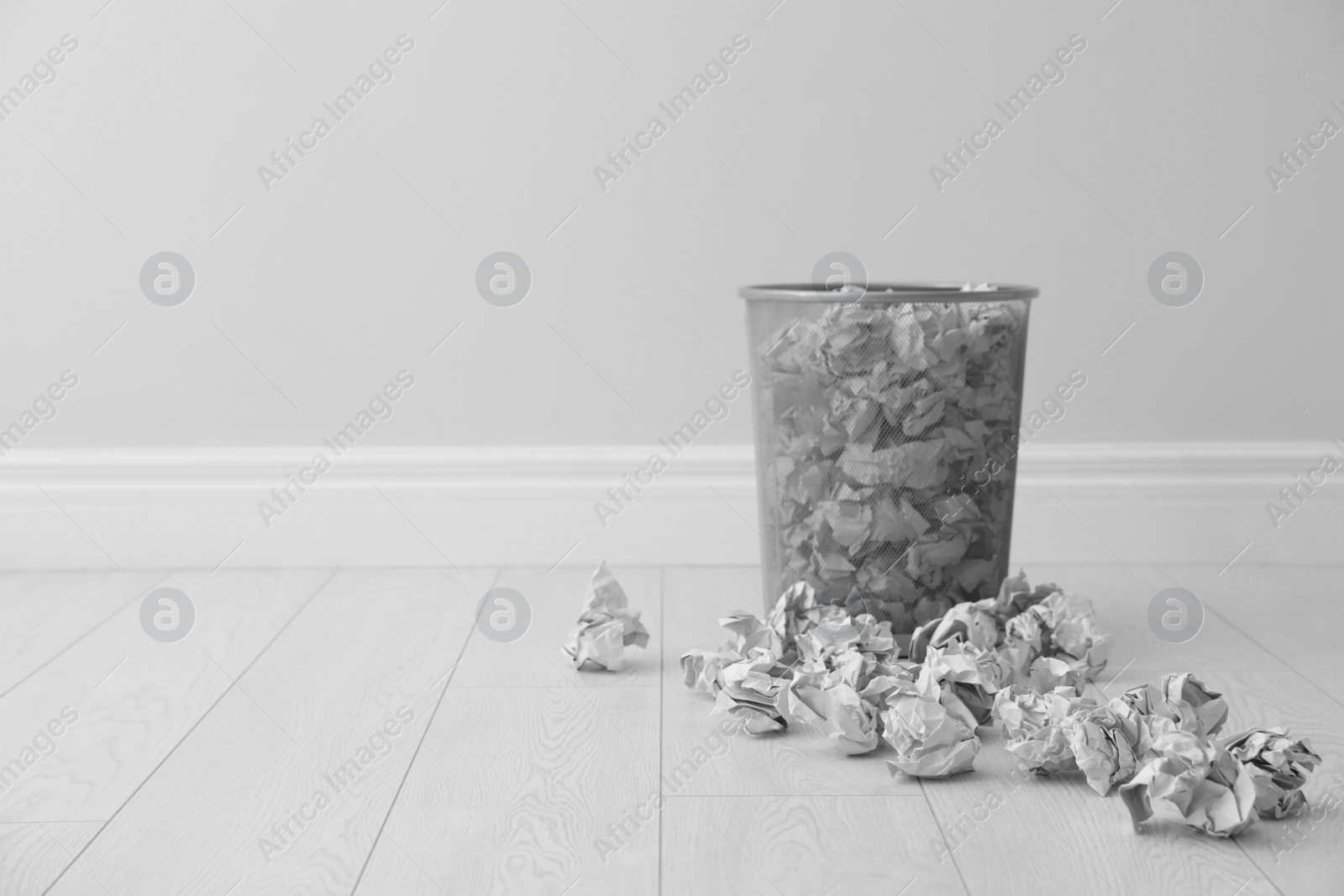 Photo of Metal bin and crumpled paper against light wall, space for text