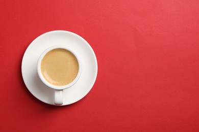 Aromatic coffee in cup on red background, top view. Space for text