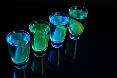 Photo of Alcohol drink with citrus wedges in shot glasses on mirror surface, space for text
