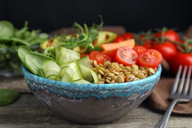 Photo of Delicious lentil bowl with avocado, tomatoes and cucumber on wooden table