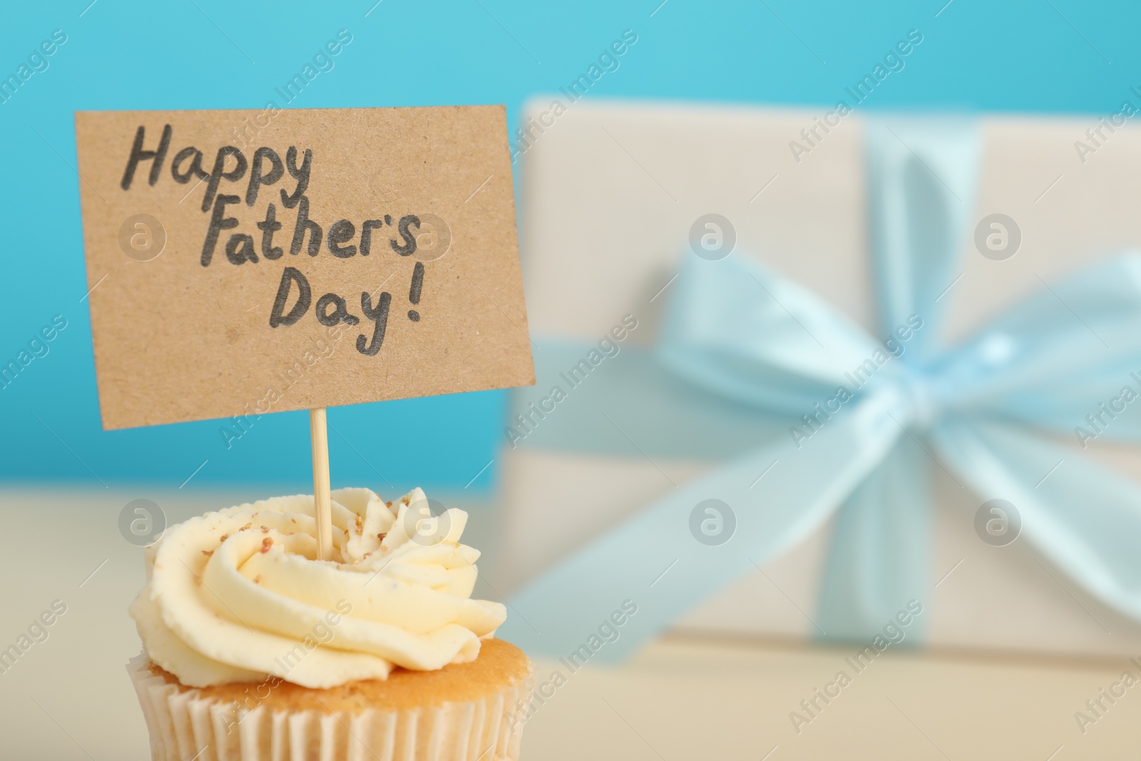 Photo of Happy Father's Day. Tasty cupcake with greetings on blurred background, closeup. Space for text