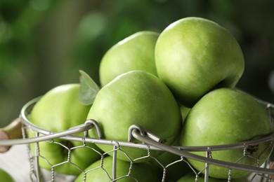 Metal basket with ripe green apples on blurred background, closeup