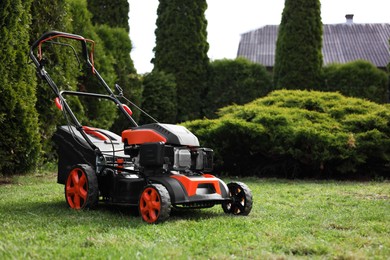 Modern lawn mower on green grass in garden