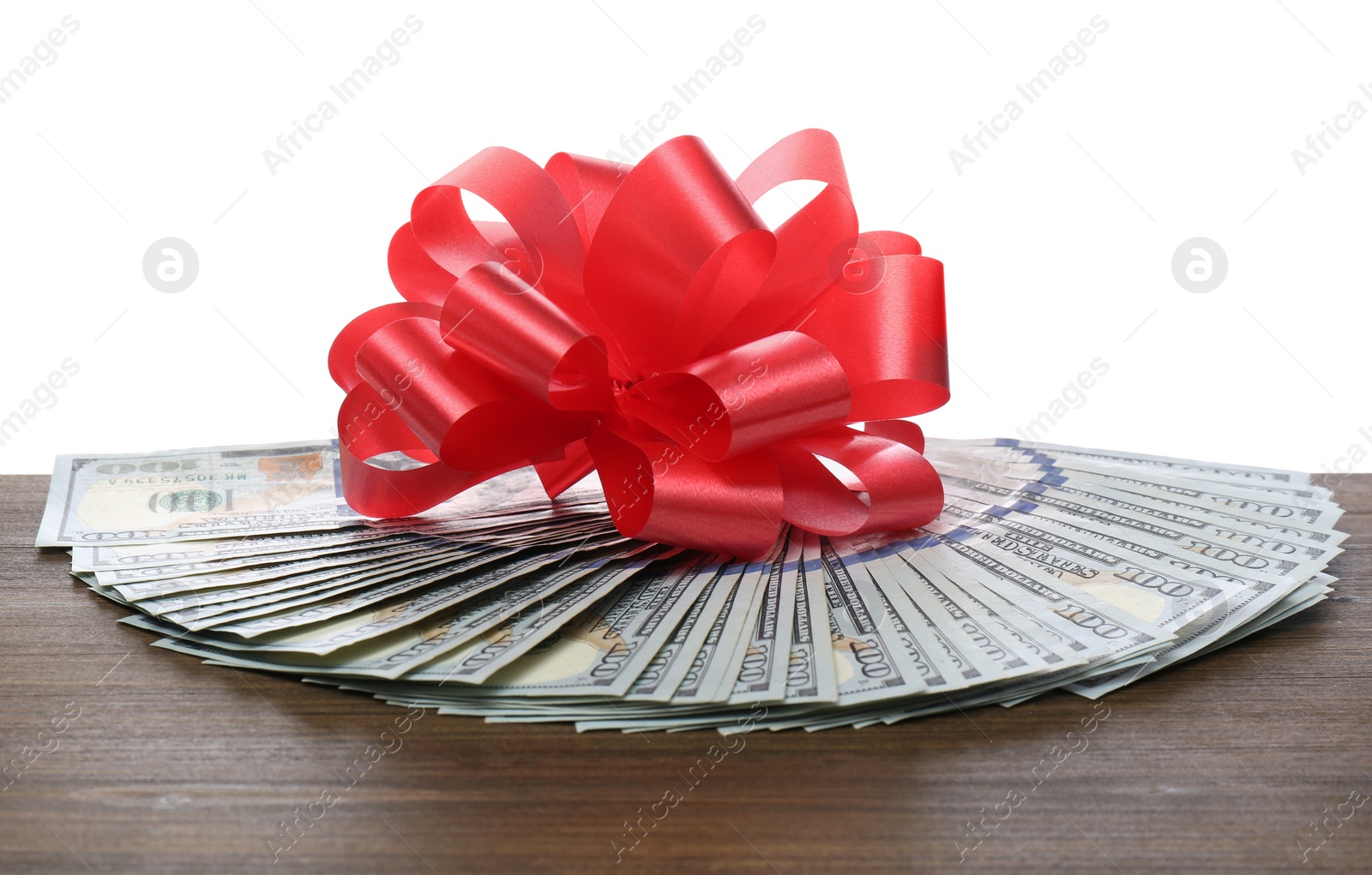 Dollar bills with red bow on wooden table against white background Photo of Dollar bills with red bow on wooden table against white background