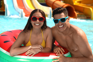 Happy couple with inflatable ring at water park. Summer vacation