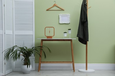 Photo of Console table with decor and coat stand in hallway. Interior design