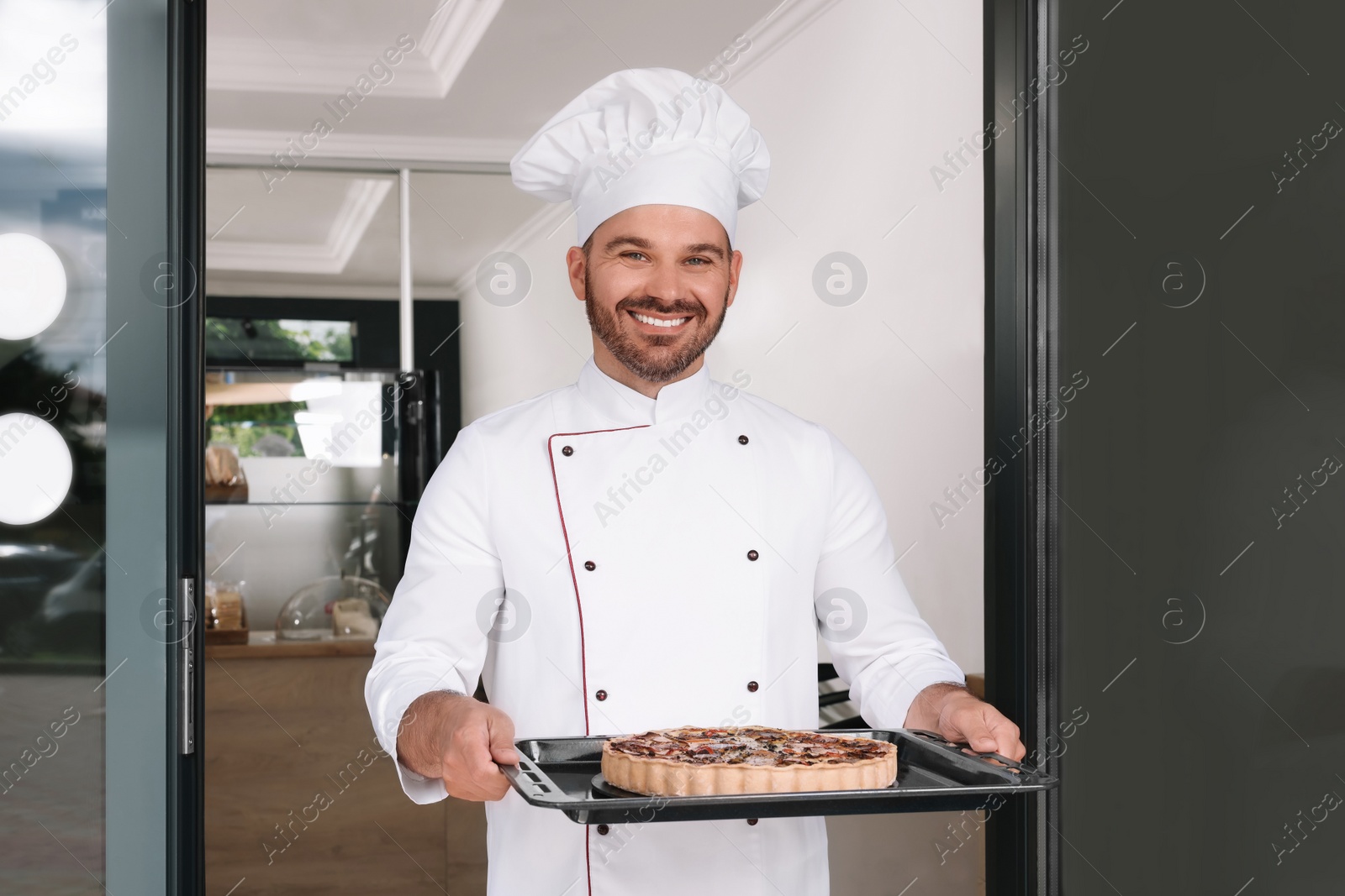 Photo of Happy baker presenting delicious quiche at door of his cafe