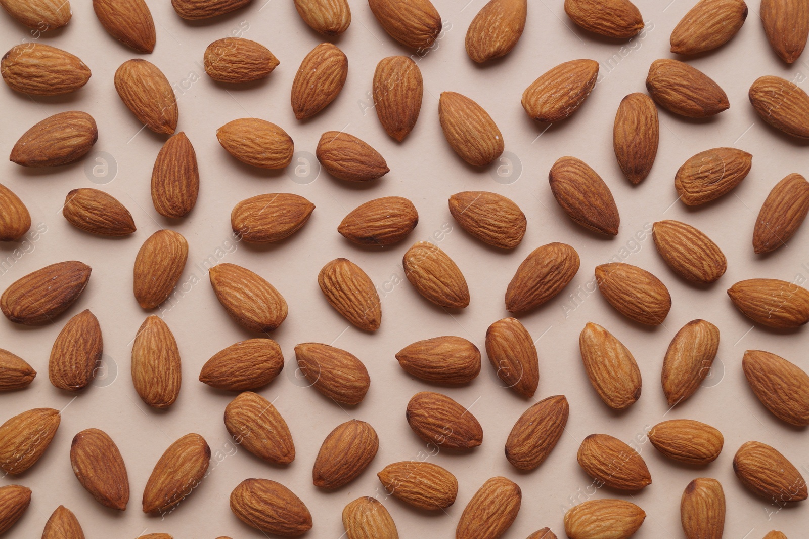 Photo of Delicious raw almonds on beige background, flat lay