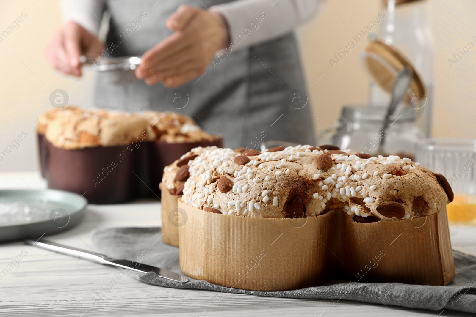 Photo of Delicious Italian Easter dove cake (traditional Colomba di Pasqua) on white wooden table, space for text