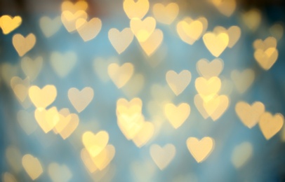 Photo of Blurred view of beautiful gold heart shaped lights on light blue background